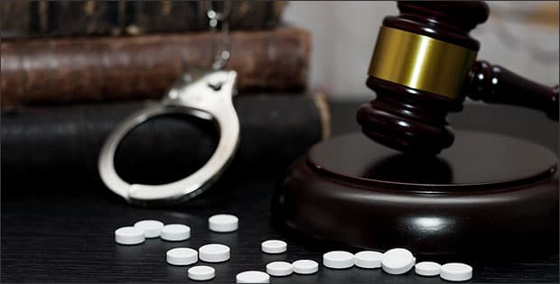 Gavel, handcuffs, and drugs depicting illegal drug manufacturing