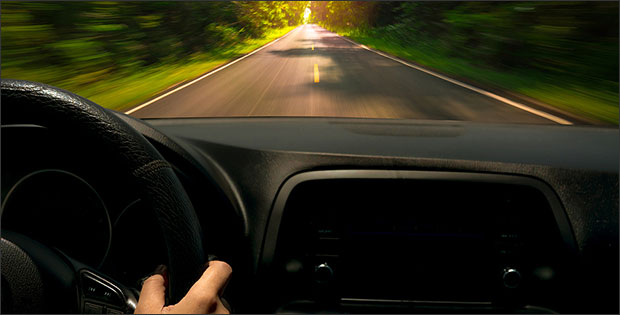 Hand on steering wheel depicting license restrictions in Michigan after a DUI.